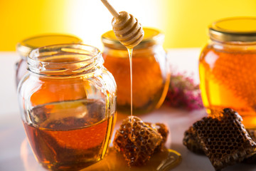 Honey in jar with honey dipper on wooden background