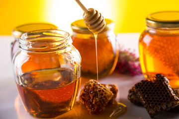 Honey in jar with honey dipper on wooden background