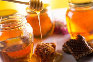 Honey in jar with honey dipper on wooden background