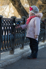 a little girl on a spring walk at the pond fenced with a wrought-iron fence