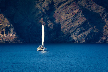 catamaran sailing near rock - obrazy, fototapety, plakaty