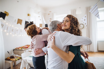 A young couple greeting parents or grandparents on indoor birthday party.