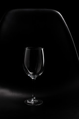 highlight of empty wine glass isolated with black chair 