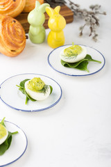 Deviled eggs with avocado and spinach and roll buns on festive Easter table