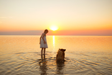 Fototapeta na wymiar little girl is walking with a dog by the sea