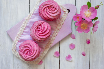 Close up sweet dessert zephyr. Homemade zephyr from currants on a white wooden background with pink flowers.