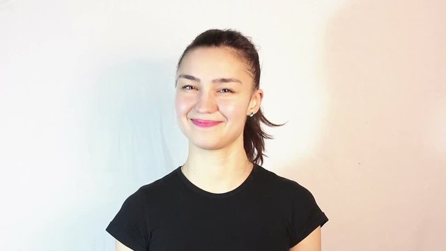 A beautiful young girl in a black T-shirt says yes and shakes her head approvingly. Portrait on a white background.