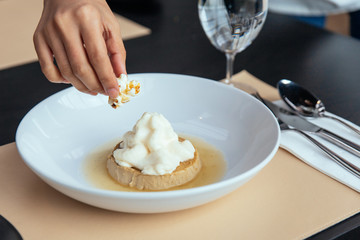 Caramel Custard with cream that topping with Popcorn. Served in white plate.