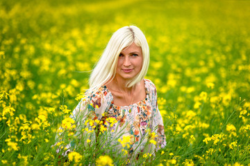 Fototapeta premium Soft, selective focus. Beautiful, attractive, blond woman in a yellow flower meadow.
