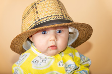 Photo of a girl in the studio, portrait of a newborn baby in a straw hat.