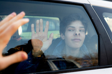 young man gold his hand on a car window and say goodbye to a friend b