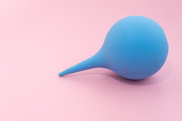 Rubber tool for clyster for medical bowel lavement on its side. Pink background. Health care