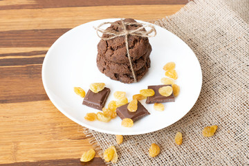 Homemade sweets for tea: chocolate pastry, raisins and slices of milk chocolate on white plate.  