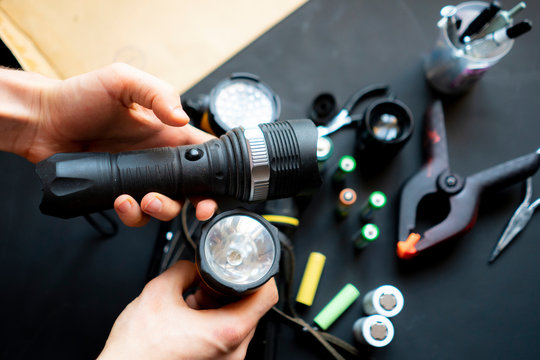 Persons Hands Hold A Flashlight In A Workshop B