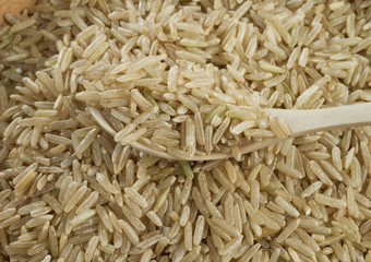 Handful of brown unpeeled rice isolated on white background.