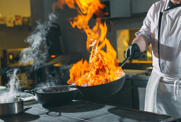 Chef is stirring vegetables in wok. - obrazy, fototapety, plakaty
