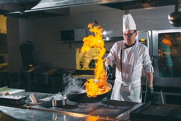 Chef is stirring vegetables in wok.