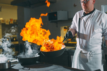 Chef is stirring vegetables in wok.