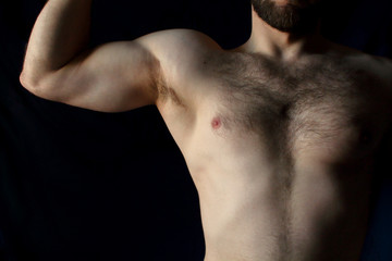 Fototapeta na wymiar Torso of brutal muscular fitness athlete of a sporty man with hairy chest against black background