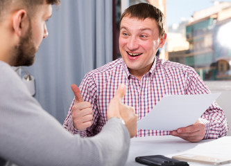 Satisfied man with partner working with documents at home