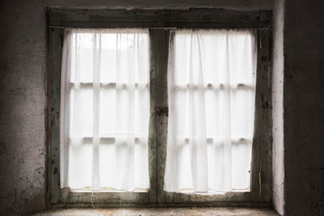 Dark old window with bricks and curtain, light coming through