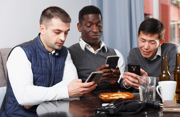 Three men with phones at home