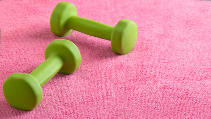 Little green fitness dumbbells on pink background