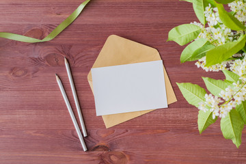 Mockup white greeting card and envelope with spring white flowers on a wooden background