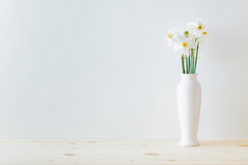 Home interior with decor elements. White daffodils in a vase  on a wooden table