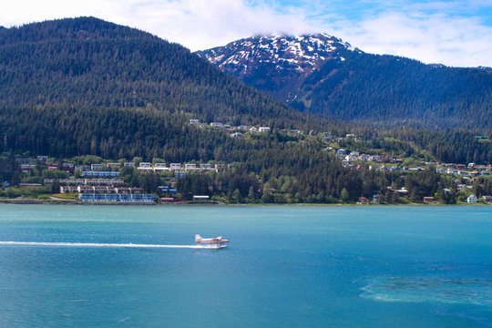 Seaplane landing in the water near a small city in Alaska.