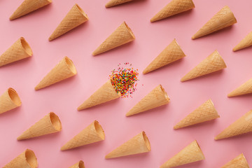 Waffle cones and sprinkles on pink surface