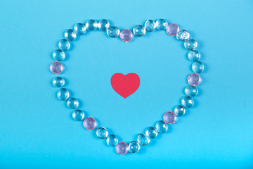 The heart of white beads and a red heart in the middle on a blue background.
