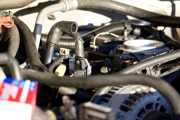 Engine compartment without air cleaner assembly, showing throttle body and components, with parts boxes in foreground, out of focus