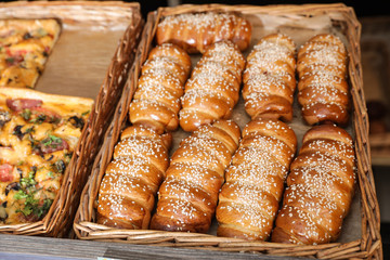 Wicker trays with fresh buns and pizza in bakery store