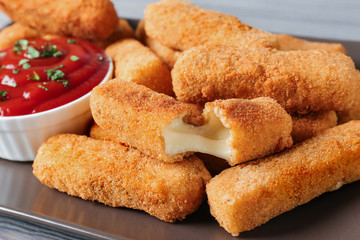 Plate of tasty crispy cheese sticks with sauce, closeup