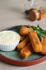 Plate of cheese sticks and sauce on table