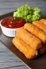 Plate of cheese sticks with sauce on table, closeup