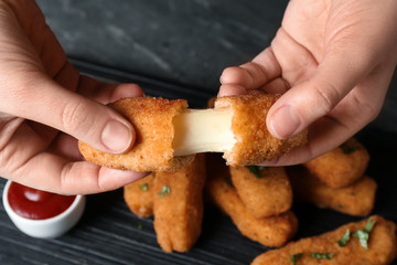 Woman holding broken cheese stick over table, top view