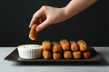 Woman dipping cheese stick into sauce at table, closeup