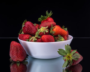 Strawberries in white dishes on a black background