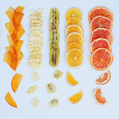 Healthy snack. Homemade dehydrated fruit chips on white background. Dry orange, grapefruit, mango, banana, kiwi. Diet food. square texture