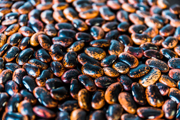 a heap of black-brown beans on black background