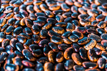 a heap of black-brown beans on black background