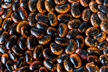 a heap of black-brown beans on black background