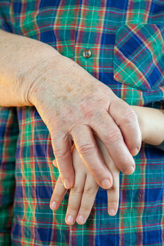 Elderly grandmother and grandson spend time together in green checkered shirt. Boy and the old woman are very attached to each other.