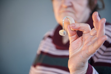 elderly retired woman with hearing impairment received hearing aid of latest modification in center of social protection and tries it on. Help for pensioners and people with disabilities