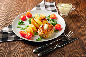Fried chicken cutlet with potato slices served with tomato cherry and corn salad. Traditional belorussian food - roasted minced meat and potato