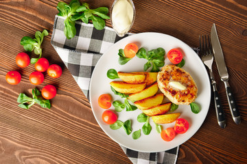 Fried chicken cutlet with potato slices served with tomato cherry and corn salad. Traditional belorussian food - roasted minced meat and potato