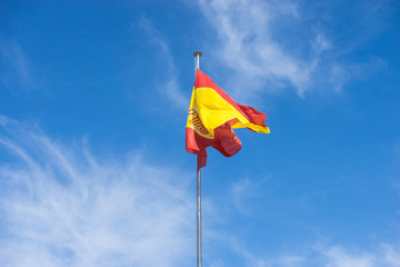 spain flag on a mast in the wind on blue sky background