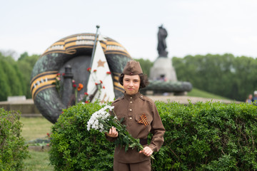 Portrait of a boy with flowers, in the uniform of a soldier of the Red Army during the Second World War. Soviet War Memorial (Treptower Park), Berlin, Germany.